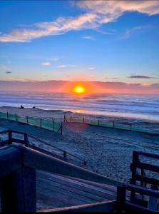 a sunset at the beach with a bench on the beach at La Parenthèse Landaise Duplex rénové avec jardin & piscine in Saint-Julien-en-Born +2 photos