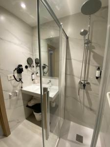 a white bathroom with a shower and a sink at Hotel Chiquín in Tapia de Casariego +22 photos
