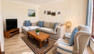 a living room with a couch and a tv at Adrenalin Addo Manor House in Addo