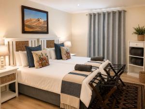 a bedroom with a large white bed and a desk at Adrenalin Addo Manor House in Addo