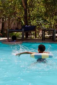 a boy in a swimming pool with a surfboard at Embe Lodge in Kizimkazi