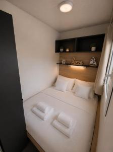 a small bedroom with a white bed with two pillows at Mobilehome Lana in Privlaka