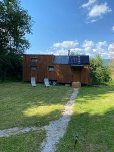 a house with two white chairs in a yard at koliBka - tiny house in Michalová