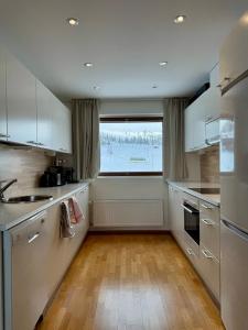 a kitchen with white cabinets and a large window at Ylläs Chalets 7305 in Ylläs