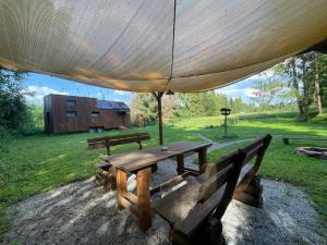a picnic table with an umbrella in a field at koliBka - tiny house in Michalová +38 photos
