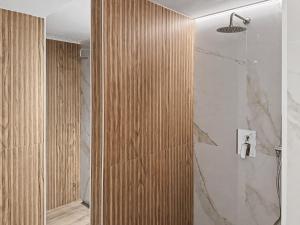 a bathroom with a shower with a wooden wall at Wellness Apartmány Pastviny in Pastviny +88 photos