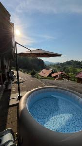 a hot tub with an umbrella on a patio at Kuća za odmor Foresta in Ladvenjak