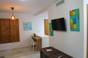 a living room with a desk and a tv on a wall at Purísima Vivienda Turística in Córdoba