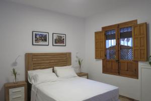 a bedroom with a white bed and a window at Purísima Vivienda Turística in Córdoba