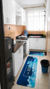 a kitchen with white cabinets and a blue rug on the floor at Kerry Luxury Stays in Athi River +4 photos