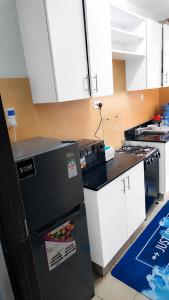 a kitchen with a black refrigerator and white cabinets at Kerry Luxury Stays in Athi River