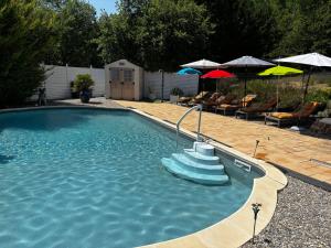 a swimming pool with chairs and umbrellas at Domaine De JI in Montagnac +16 photos