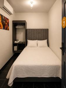 a bedroom with a large bed with white sheets at Barrio Inn Padre Mier Hostal & Suites in Monterrey