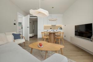 a living room and kitchen with a table and chairs at PINEA Apartamenty in Pobierowo