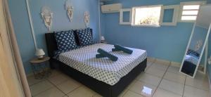 a bedroom with a bed with blue walls and a window at Fleur de Canne in Saint-Pierre