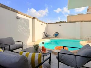 a patio with a swimming pool with chairs and a table at Ultimate Group Getaway Near St Julian's & Seafront in San Ġwann