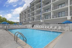 a pool in front of a hotel with chairs and umbrellas at Best Western Plus Ocean City in Ocean City