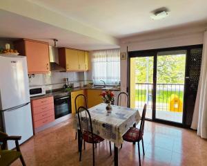 a kitchen with a table with chairs and a white refrigerator at Miramar Playa confortable apartament in Miramar +11 photos