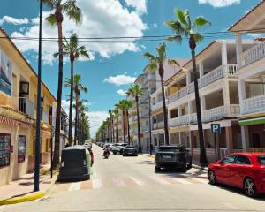 a street with palm trees and cars parked on the street at Miramar Playa confortable apartament in Miramar