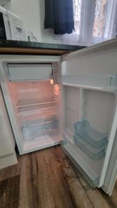 an empty refrigerator with its door open on a wooden floor at hostal olozaga in Alicante
