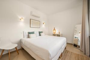 a white bedroom with a white bed and a chair at Vilamoura 4-Bedroom Private Pool Villa in Vilamoura