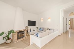 a white living room with a couch and a fireplace at Vilamoura 4-Bedroom Private Pool Villa in Vilamoura