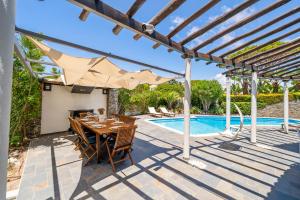 a patio with a table and umbrella next to a pool at Vilamoura 4-Bedroom Private Pool Villa in Vilamoura