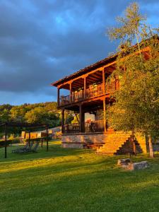 a large wooden building with a deck on the grass at Leshten Guest Homes in Leshten