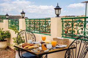 a table with food and orange juice on a balcony at Riad Nassim Fez in Fez