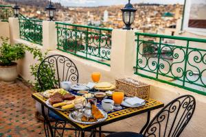 a table with food and orange juice on a balcony at Riad Nassim Fez in Fez +97 photos