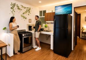 a man and woman standing in a kitchen with a black refrigerator at Nagomi Casa amplia para empresas, grupos y familias in Pachuca de Soto