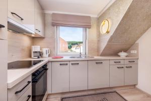 a kitchen with white cabinets and a window at Ferienwohnung Rosen am Meer in Sassnitz +6 photos