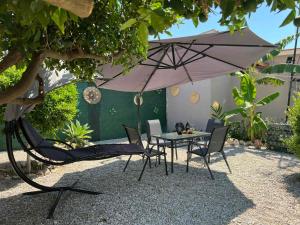a table and chairs under an umbrella in a garden at Sunny house in Kremasti
