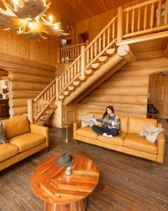 a woman sitting on a couch in a cabin at Blue Moose Private pool spa sauna lake access in Wentworth