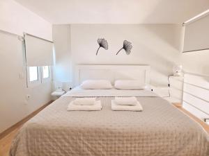 a white bedroom with a large bed with two towels at Loft Suites - by Avelink in Spata