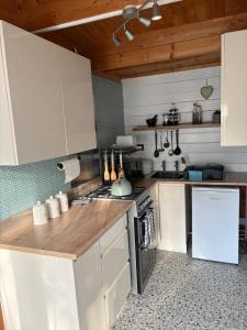 a kitchen with white cabinets and a stove top oven at Modern Cabin with large private garden in Old Romney +23 photos