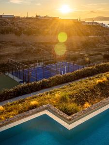 a swimming pool with a sunset in the background at San Antonio Summerland in Mikonos