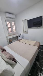 a bedroom with two beds and a tv on the wall at Pension Susita in Alicante