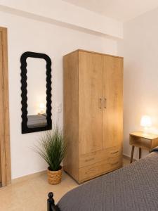 a bedroom with a wooden cabinet and a mirror at Musses apartment 1 Modern Studio with Free Parking in Limín Khersonísou