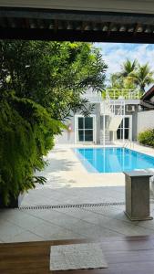 a swimming pool with a bench in front of a house at Pousada do Tio Cido in Guarujá