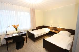 una camera d'albergo con 2 letti e una scrivania di Hotel Kröger a Ennigerloh