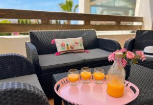 a table with three glasses and a bottle of orange juice at Asilah Cozy Pieds dans l'eau in Asilah