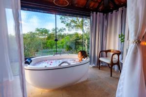 a woman in a bathtub in a room with a window at Royal Turquesa Boutique Hotel in Búzios