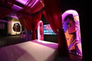 a bedroom with a bed with red curtains at L'amour Hotel in Ho Chi Minh City