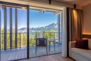 a room with a balcony with a couch and a chair at Hotel Olangerhof in Valdaora +153 photos