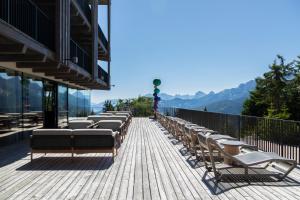 a row of chairs on a balcony with mountains in the background at Hotel Olangerhof in Valdaora
