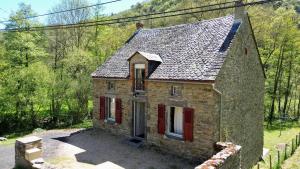 an old stone house with red shutters on a yard at Gite l'Entre Deux O' in Blesle