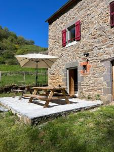 a picnic table with an umbrella in front of a stone building at Gite l'Entre Deux O' in Blesle