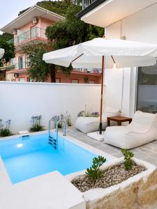 an outdoor swimming pool with an umbrella and chairs and a swimming poolvisor at Ιόνια Γαλήνη Pool Spa Suite in Parga