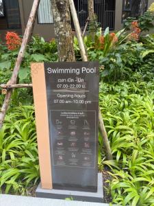 a sign for a swimming pool in a garden at The Base Central Phuket-a modern comfort condo-sso in Ban Rangeng